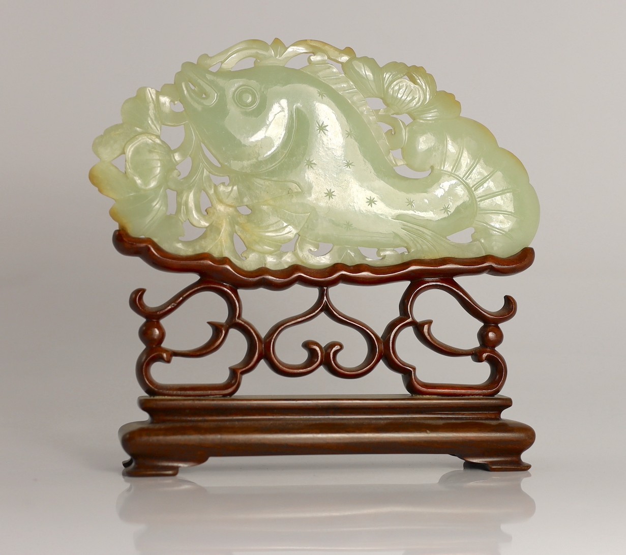 A Chinese pale celadon jade 'fish' plaque, 18th/19th century, 16.7cm long, 8.5cm high, later wood stand for use as a table screen